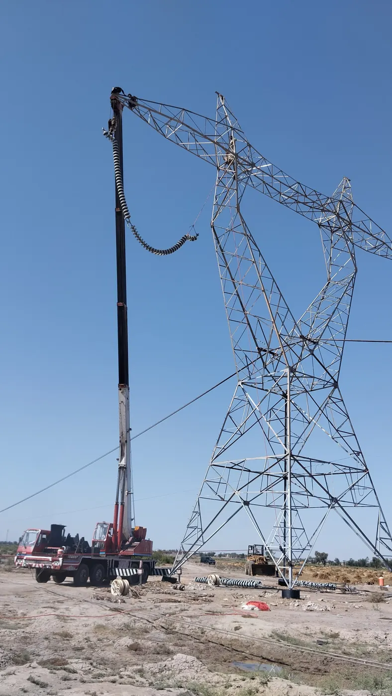 Crane lifting an insulator string to the crossarm