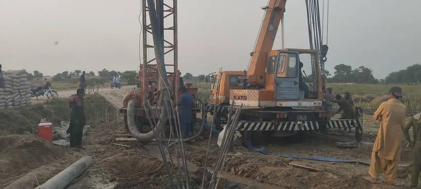 Piling rig and crane at work with cement stacked on site